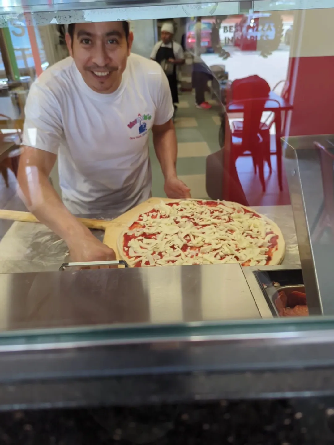 Pizza maker at the Moravela’s counter with a fresh pie